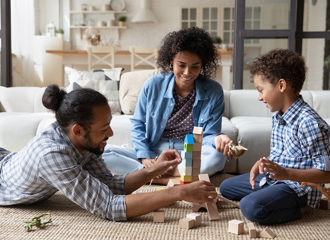 Personal Insurance - Happy Family and Young Son Playing With Building Blocks in the Family Room on the Floor